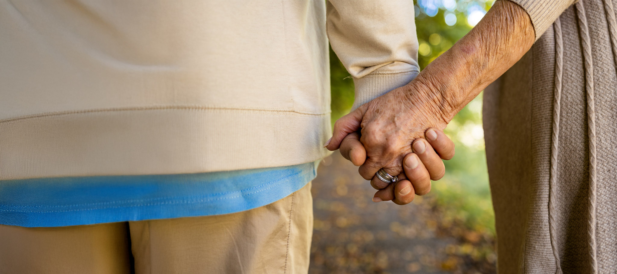 älteres Paar hält sich die Hände auf einem Feldweg